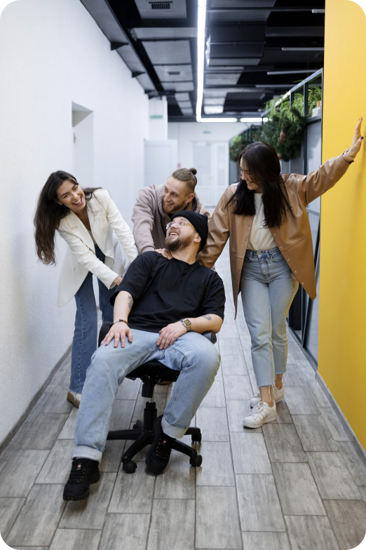 image showing four members of the London team in casual wear being playful in a hallway at the office